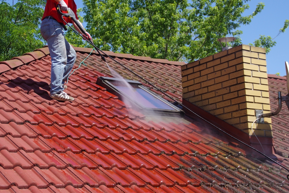 Man,On,Rooftop,Sprays,Water,,Cleaning,Surface.,Concept,Of,Maintenance, Nettoyage toiture Blanquefort